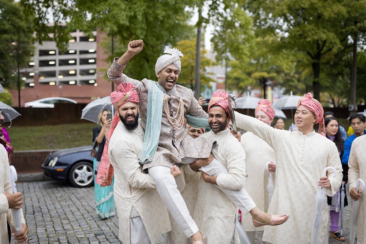 Baraat celebration with groom lifted by groomsmen