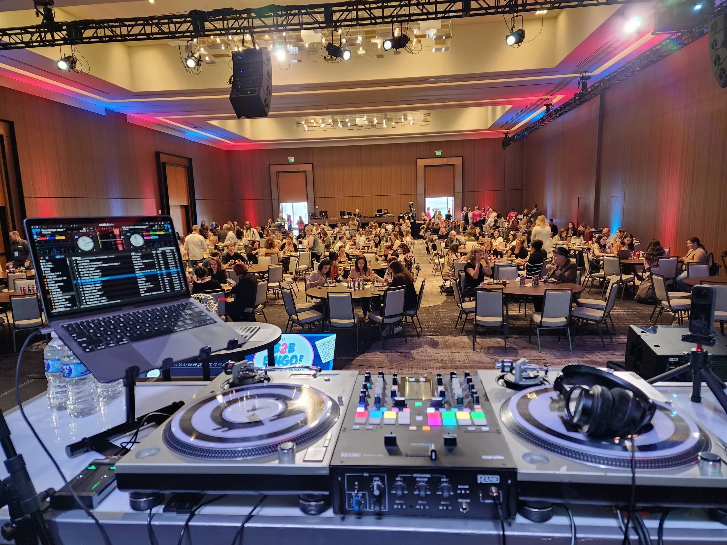 DJ Taj Productions setup at large corporate gala with DJ equipment overlooking ballroom full of guests