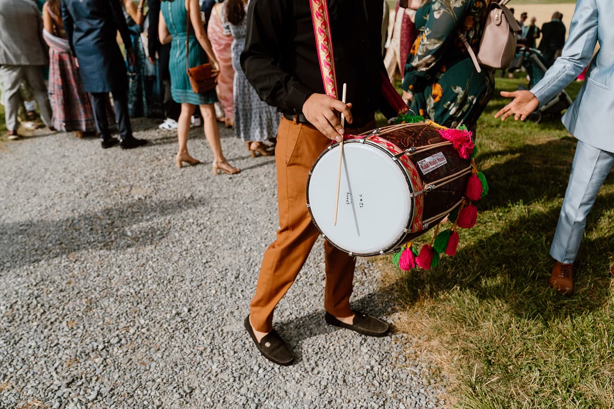 Dhol player walking outdoors at sangeet event